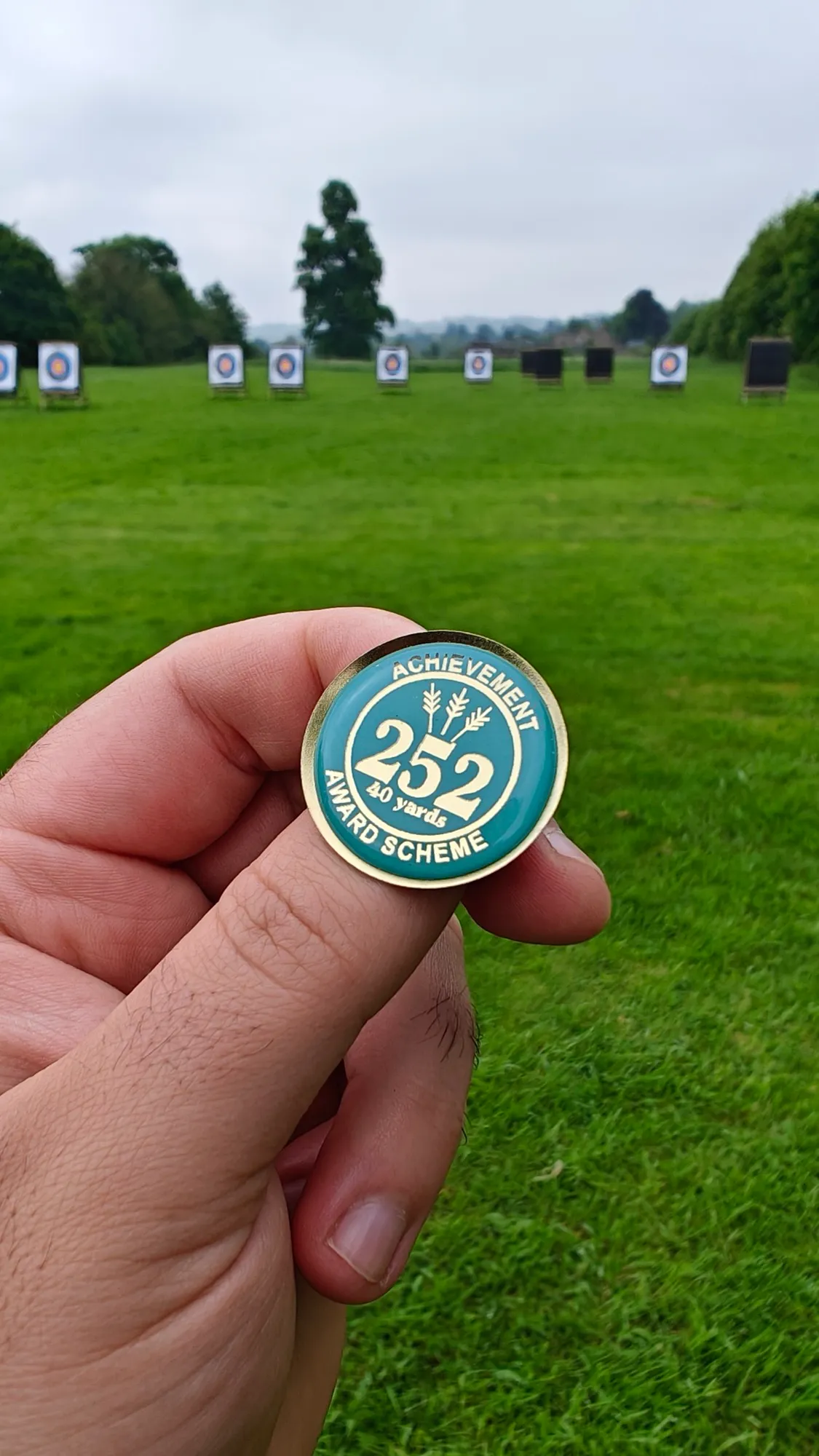 A 40-yard 252 Achievement Award badge held up in front of targets on the field