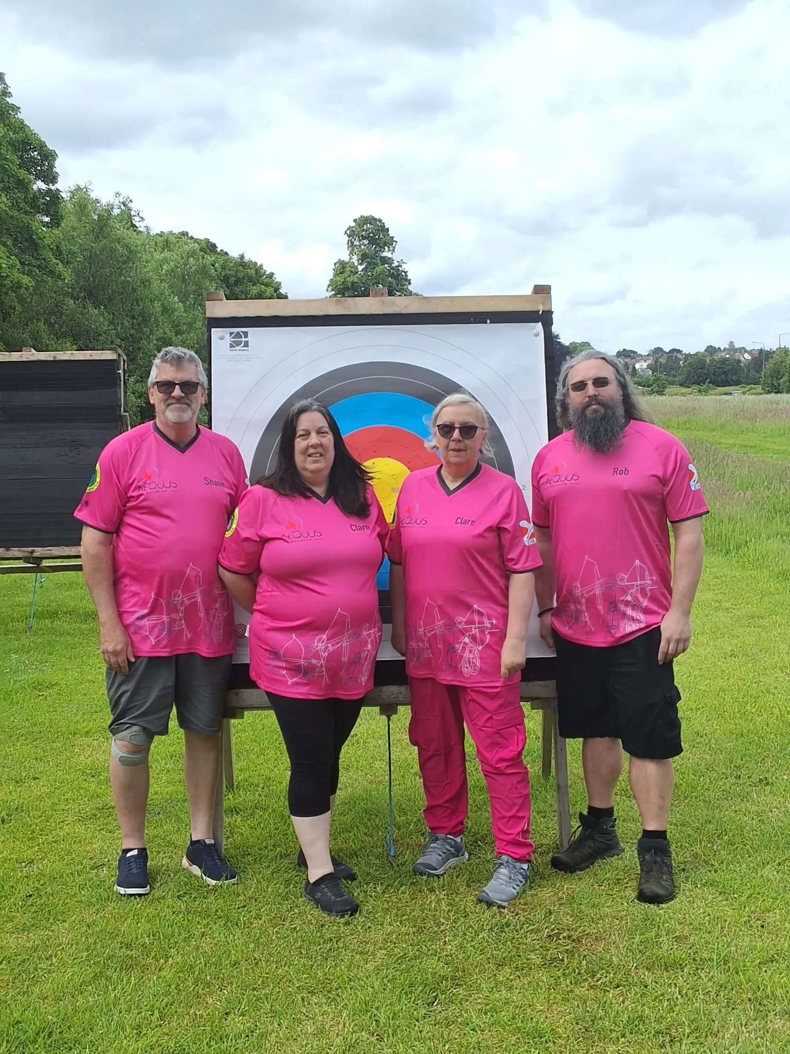 Four Aequus Archers coaches in matching pink shirts in front of a target