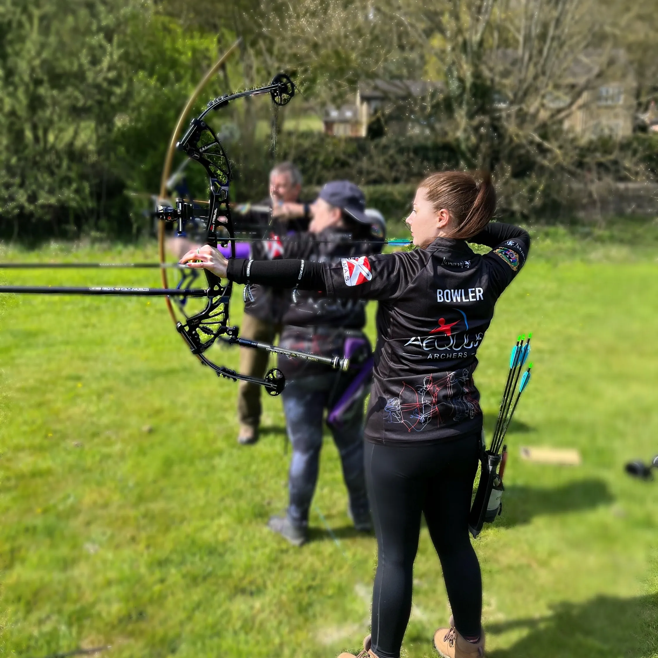 Three Aequus Archers members shooting side by side on the line