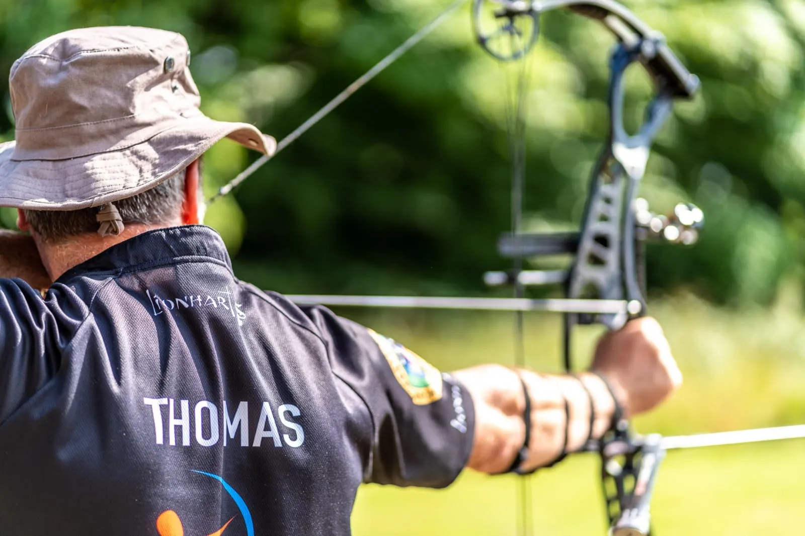 A club member drawing a compound bow on the field at Milford
