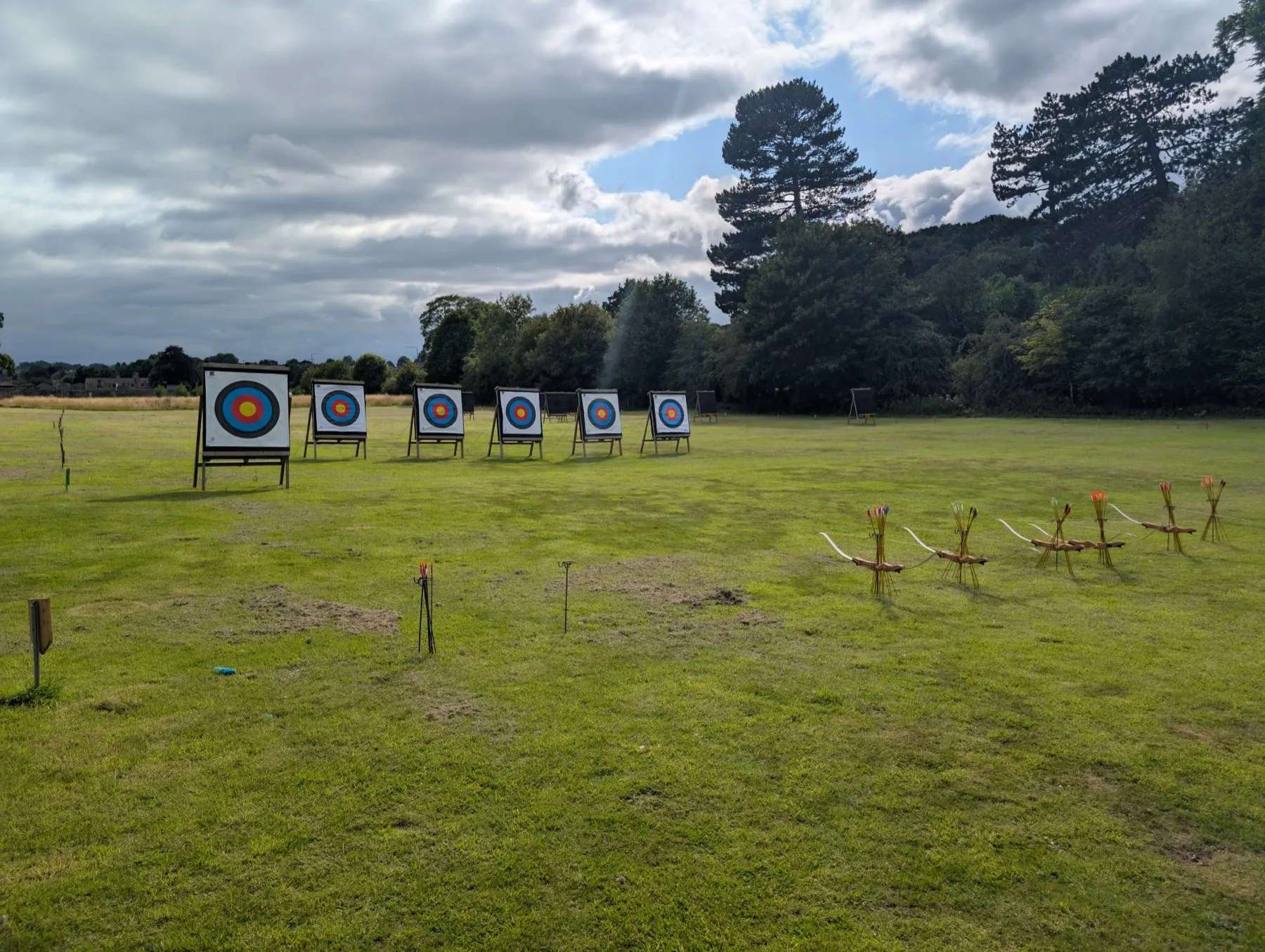 Targets and a row of loan bows laid out on the grass before a taster session